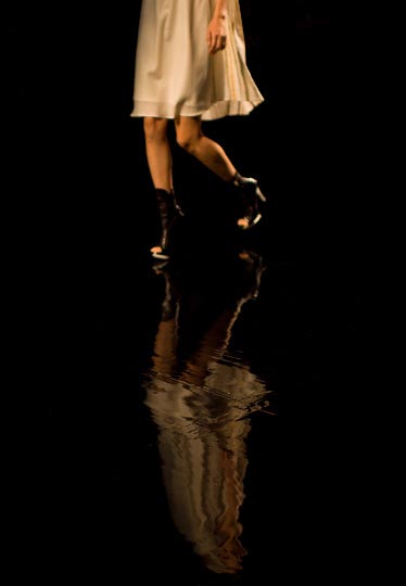 Photographer danny roberts image of the bottom half of a girl in a white dress and black shoes and her reflection off the floor in Araisara Tokyo Fashion week Spring 2012 Collections