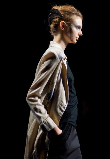 Artist Danny Roberts profile Picture of a female model in a beige over coat and black clothes underneath in Yasutoshi Exumi spring 2012 collection at tokyo fashion week